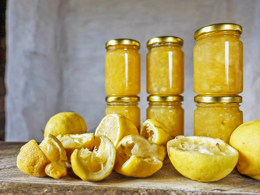 Glasburkar med citronmarmelad och citroner. Glass jars with lemon marmalade.