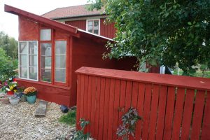 Rödmålat växthus och staket.