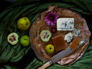 En ostbricka med gele av rosenkvitten och blåmögelost samt några färska kvittenfrukter.