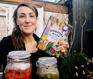 Jenny Neikell bland mjölksyrade grönsaker med  sin bok Fermentera 2.0 i handen