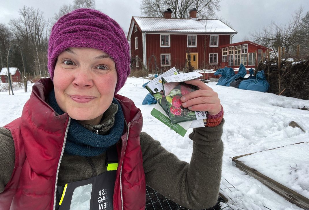 Sara's sowing seeds with a red house in the background.